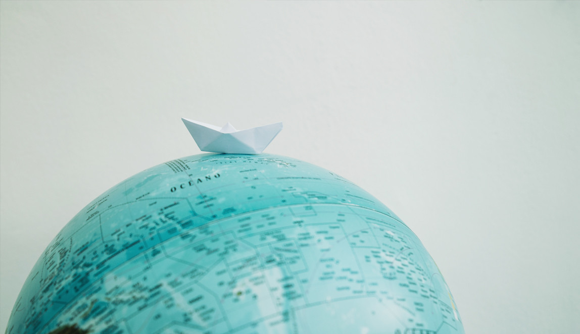 A globe with a paper boat on top
